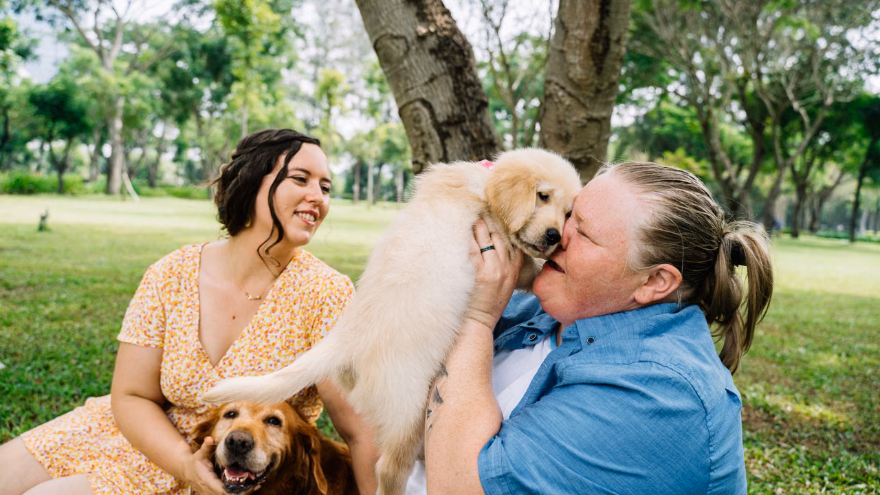 Two women hugging a golden retriever puppy in a park, ESA letter in Arkansas