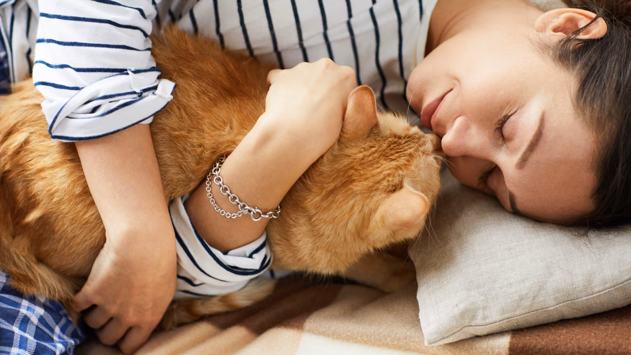 Woman hugging her ginger cat in bed, ESA letter in Portland, ME