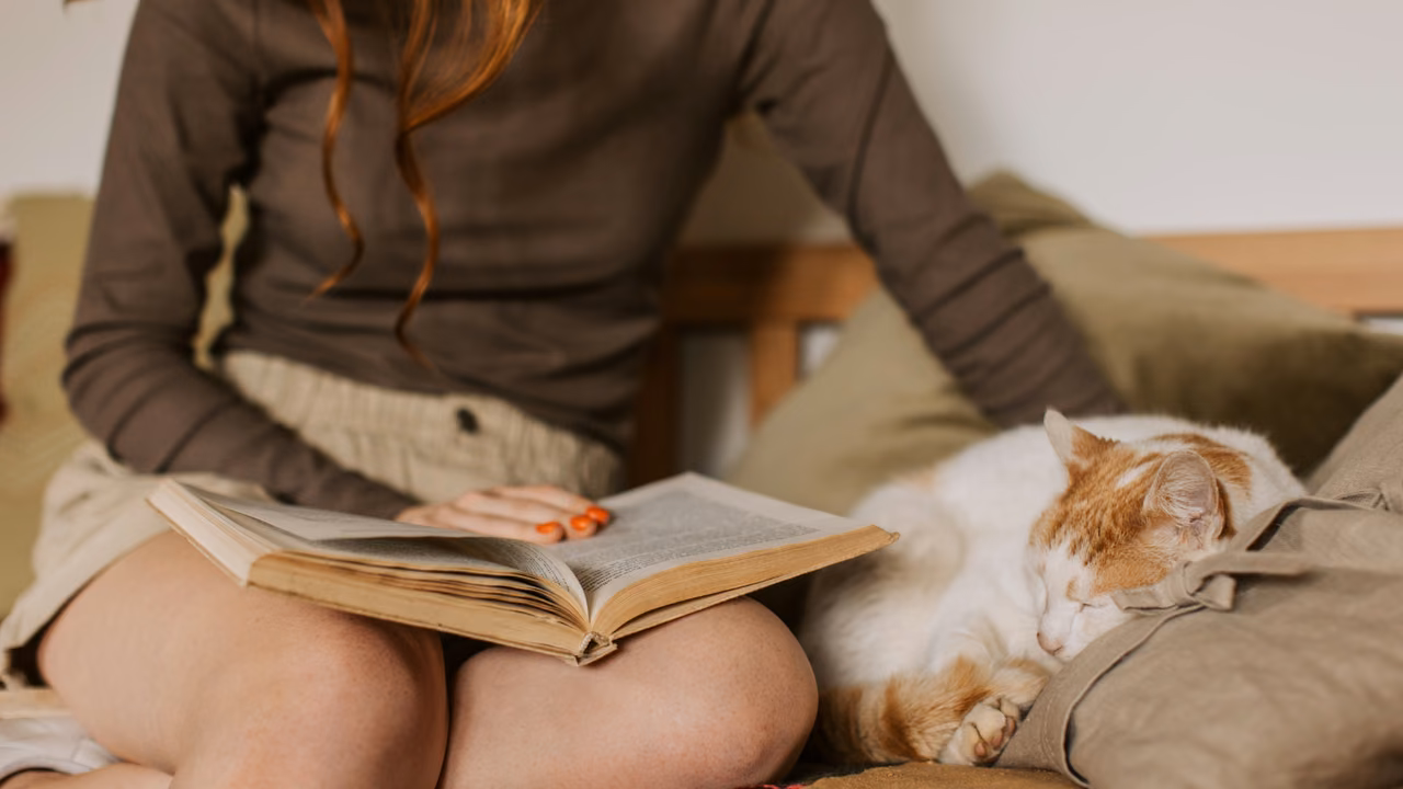 Woman reading a book next to her cat, ESA letter in Portland, OR